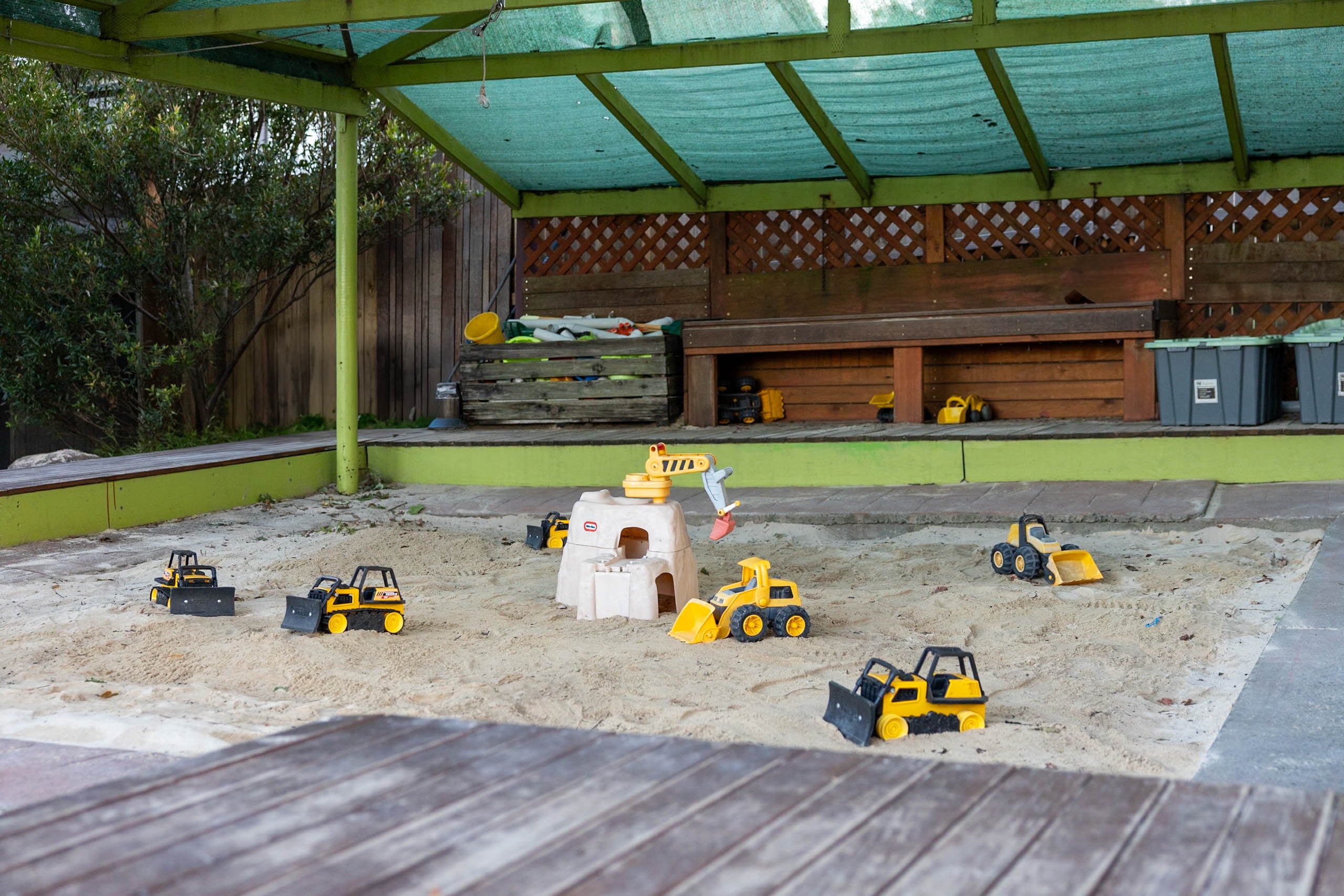 Covered sandpit with toy trucks